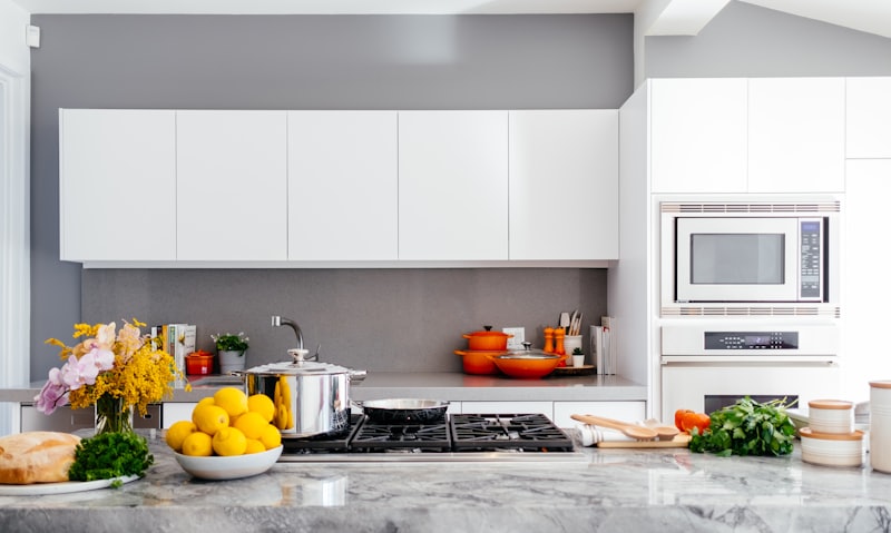 Bright modern white kitchen with marble worktop and gas hob